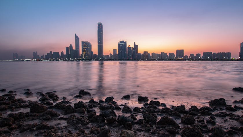 City skyline at sunset reflecting in the water, representing affordable living options and cheap property for sale in UAE.