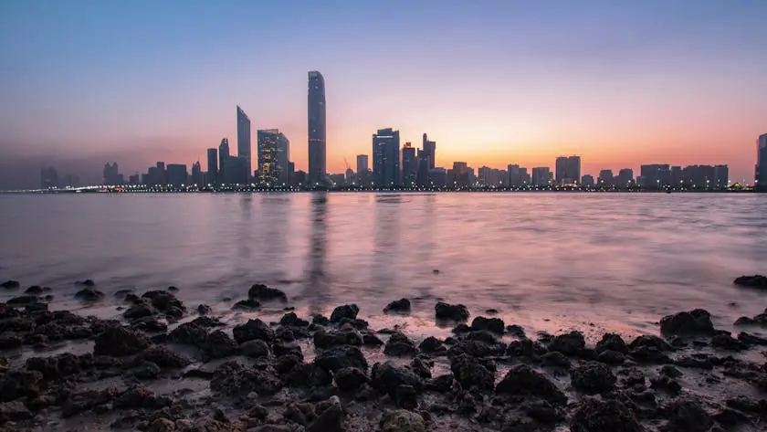 City skyline at sunset reflecting in the water, representing affordable living options and cheap property for sale in UAE.