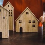 Wooden house models with stacked coins, symbolizing financial management for UAE property investments