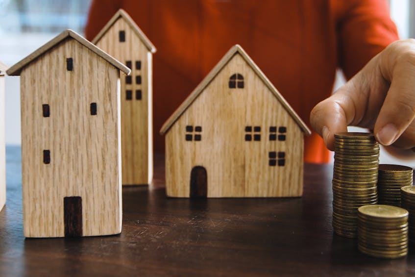 Wooden house models with stacked coins, symbolizing financial management for UAE property investments