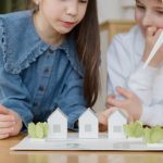 Children learning about sustainability in property management through a model of eco-friendly houses and a wind turbine, promoting green living