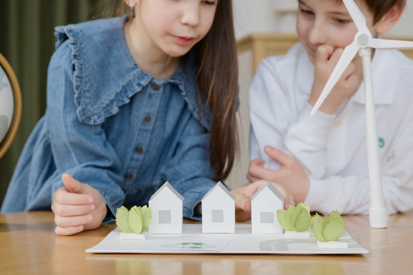 Children learning about sustainability in property management through a model of eco-friendly houses and a wind turbine, promoting green living