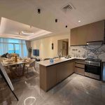 Modern open-plan kitchen and dining area in an off-plan vs. ready-to-move-in property in UAE, featuring sleek cabinetry and marble flooring.