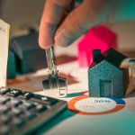 2 house models, key, a calculator, and a percentage of financing a house shows the buyer choose one of the developer vs financing options in ajman to buy property